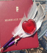 feather pens with marriage register and red heart paperweight